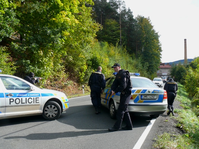b) čeští policisté tvoří zábranu na silnici